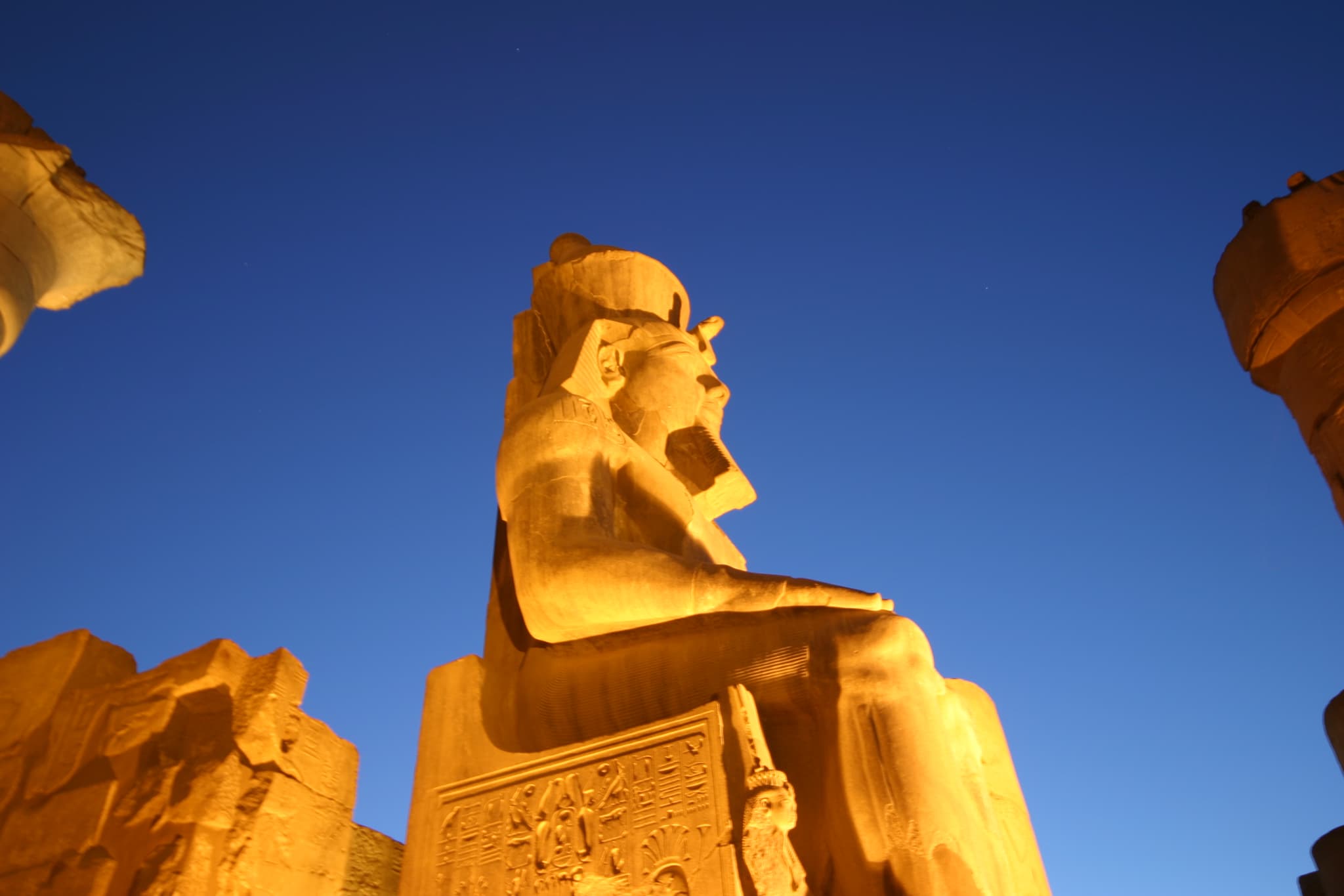 A colossal statue of Ramses II glowing at dusk at Luxor Temple