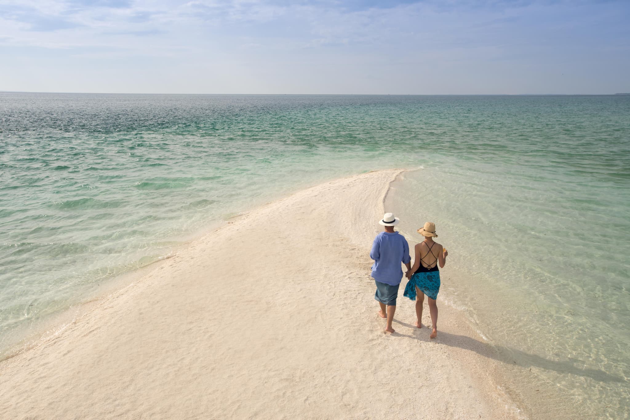 Couple walking along a white sandbar into the Indian Ocean