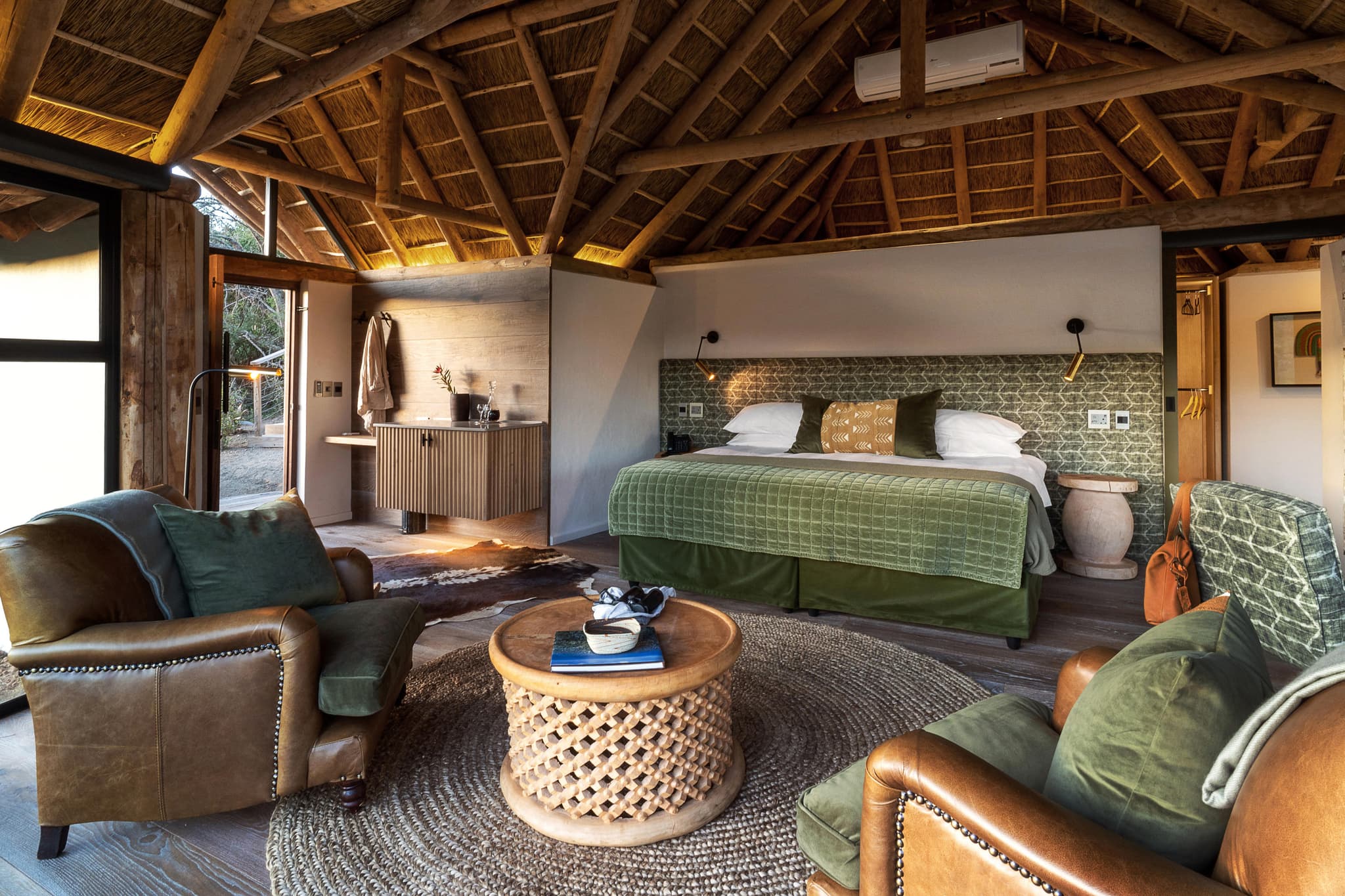 Thatched-roof lodge suite with leather armchairs at Great Fish River Lodge