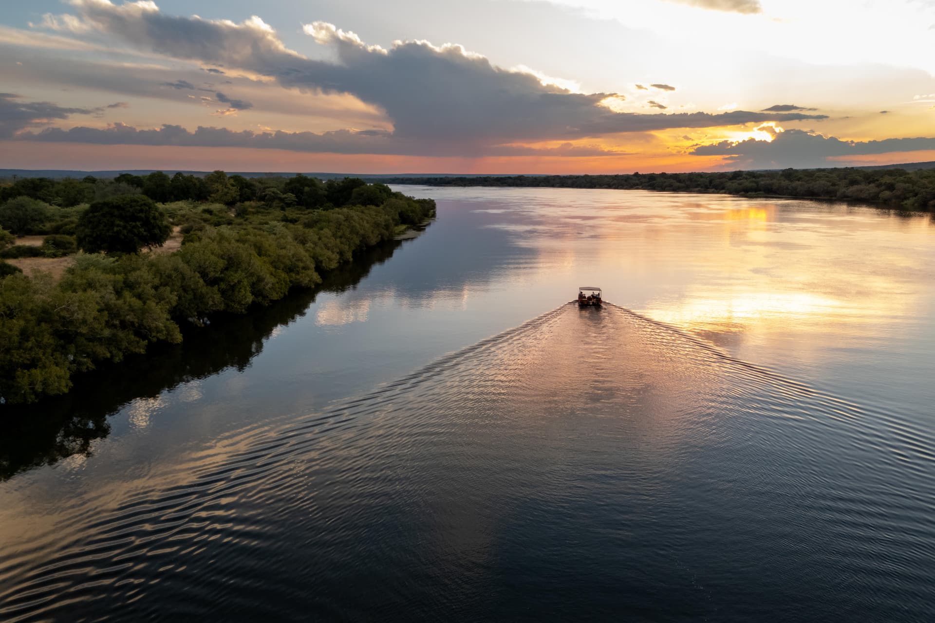 Boat cruising on the Zambezi River at sunset