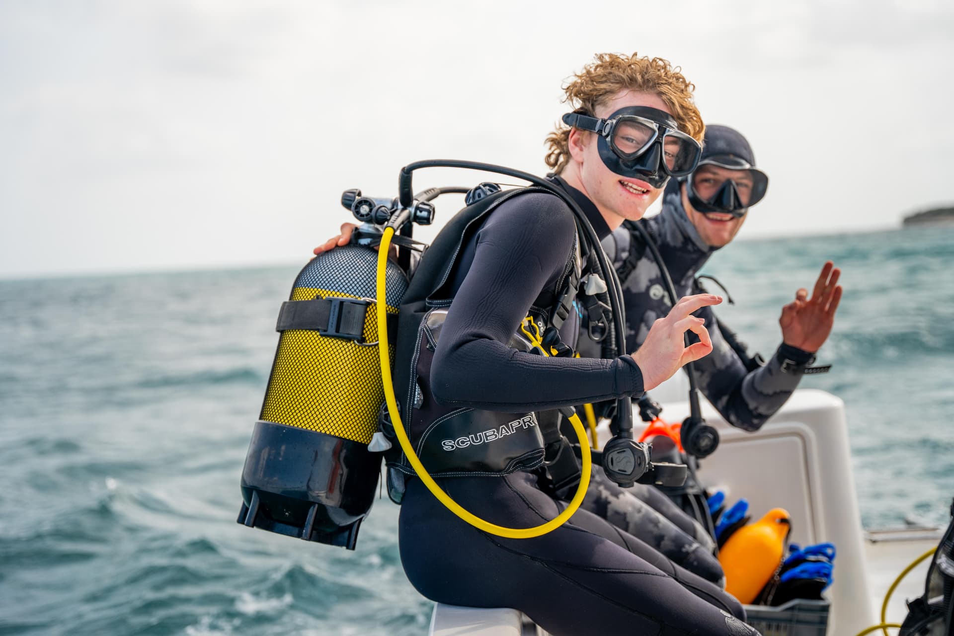 Young scuba divers in full gear on a boat ready to dive
