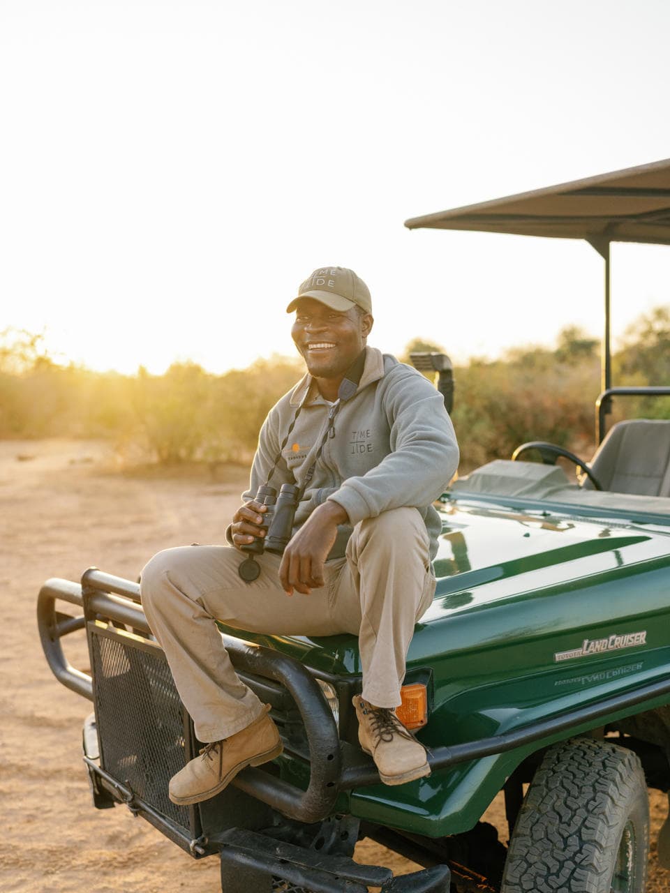 Smiling safari guide with binoculars on a Land Cruiser